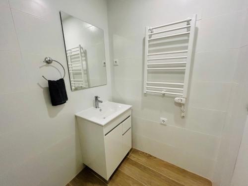a white bathroom with a sink and a mirror at Rooms Chima in Madrid
