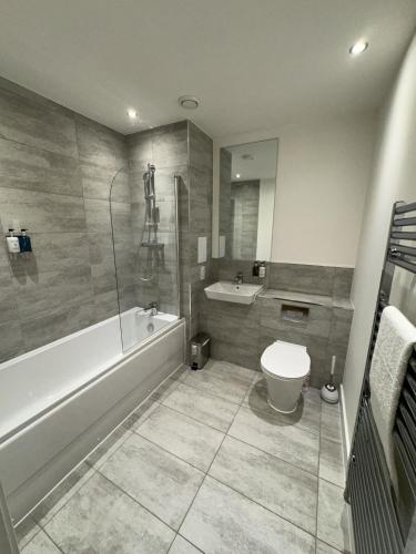 a bathroom with a tub and a toilet and a sink at Kimpton Rooms Luxury Apartment By Luton Airport in Stopsley