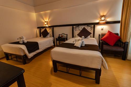 a hotel room with two beds and a chair at Hotel Kapac Inn-San Blas in Cusco
