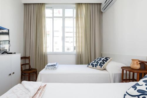 ein Hotelzimmer mit zwei Betten und einem Fenster in der Unterkunft Vista lateral mar, rua tranquila e arborizada in Rio de Janeiro