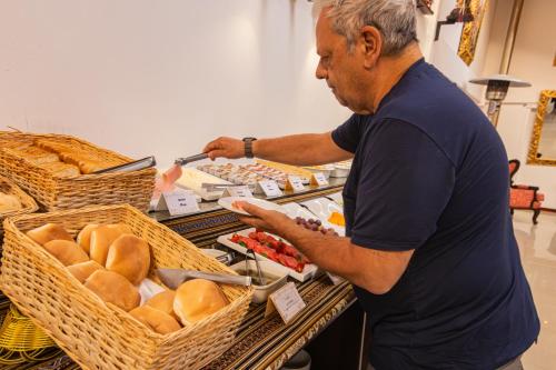 a man standing in front of a table with baskets of bread at Hotel Kapac Inn-San Blas in Cusco