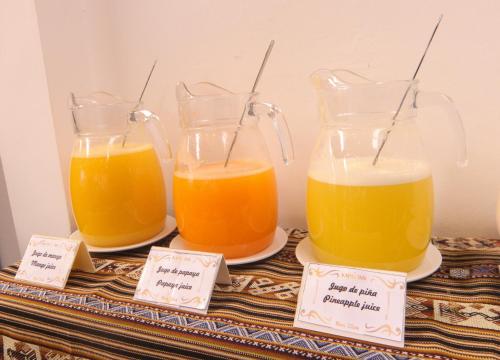 three glass containers of orange juice on a table at Hotel Kapac Inn-San Blas in Cusco