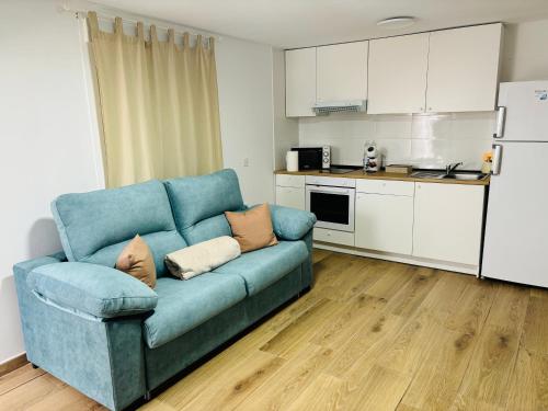 a blue couch in a living room with a kitchen at Libertad B in Santiponce