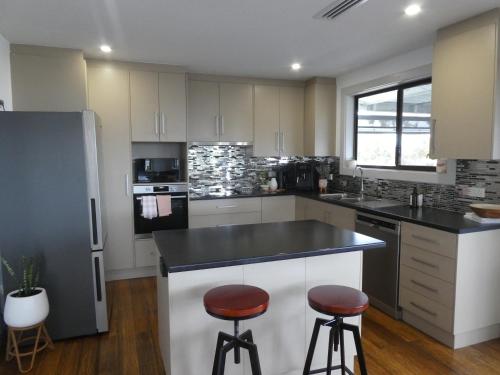 a kitchen with white cabinets and black counter tops at Moonta Bay Stylish large home 3 min walk from beach and jetty in Port Moonta