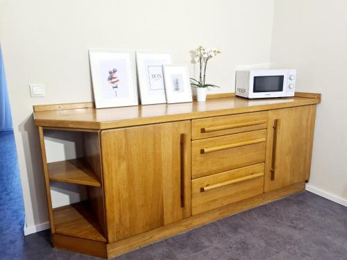 a wooden cabinet with a microwave and pictures on it at Giertensmühle Mesenich in Langsur