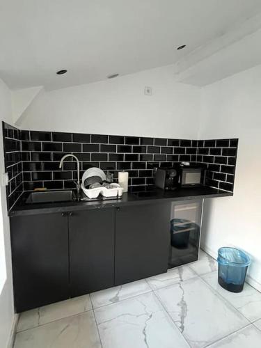 - une cuisine avec un évier et un mur en briques noires dans l'établissement Love room jacuzzi proche centre ville, à Amiens