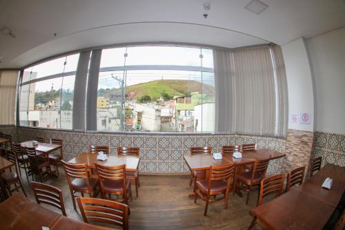 a restaurant with tables and chairs and a large window at Hotel Maria da Fé in Aparecida