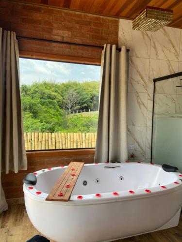 a bath tub in a room with a window at Chalé Magia do Serrano in São Bento do Sapucaí