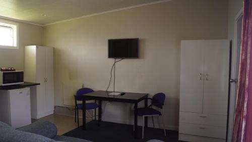 a room with a table and chairs and a television at Apple Motor Inn in Hastings