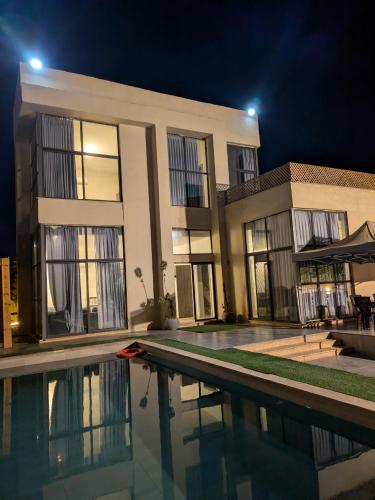 a villa with a swimming pool at night at Aeropuerta Mini Villa - Private self check-in Layover near Amman Airport in Al Qasţal