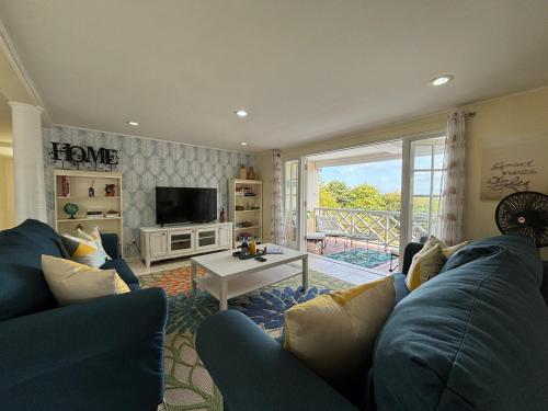 a living room with a blue couch and a tv at Private villa with large pool & 5min walk to beach in Cap Estate