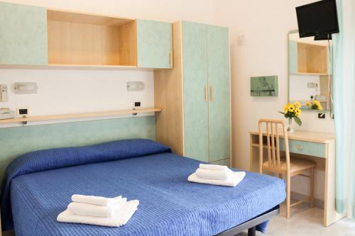 een slaapkamer met een blauw bed en handdoeken bij Hotel Buda in Bellaria-Igea Marina