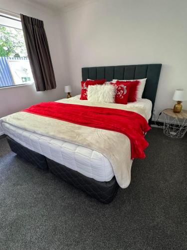 a bedroom with a large bed with red and white pillows at Centre Court Motel in Blenheim