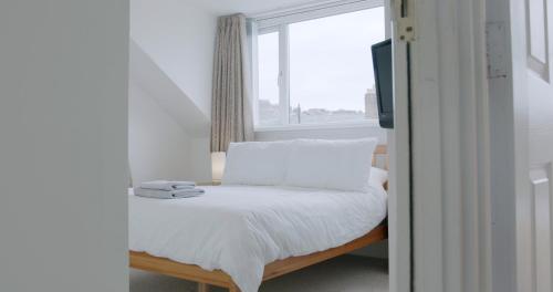 a bedroom with a bed with white sheets and a window at Entire 8 Ensuite Bedroom Coastal Holiday Home Townhouse, Free Parking, Fully Equipped Kitchen, Dining Room & Lounge, Perfect for Family Gatherings, Long Term Contractor, Relocation, etc Stays, 20 mins to Sunderland & Newcastle, See our Site for Assurance in South Shields