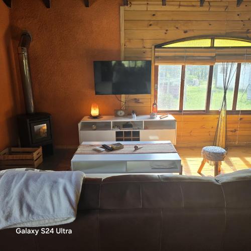 a living room with a couch and a flat screen tv at Cabaña MISUEÑO in Punta Del Diablo