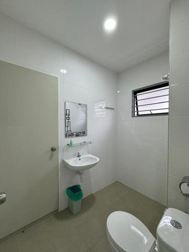 a white bathroom with a toilet and a sink at Sungai Long Guesthouse in Kajang