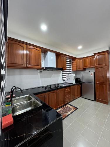 a kitchen with wooden cabinets and a stainless steel sink at Sungai Long Guesthouse in Kajang