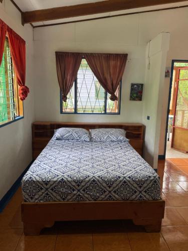 a bedroom with a bed and two windows at Cabinas Caribe Luna in Cahuita