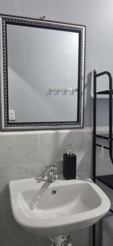 a white sink and a mirror in a bathroom at Habitaciones y Cabañas El Sauce in Tela