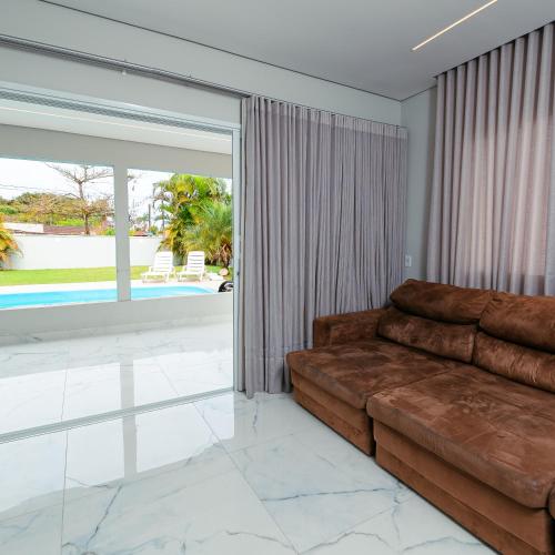 a living room with a couch and a large window at M&M House - Casa com Piscina e Ar Condicionado em Matinhos in Matinhos