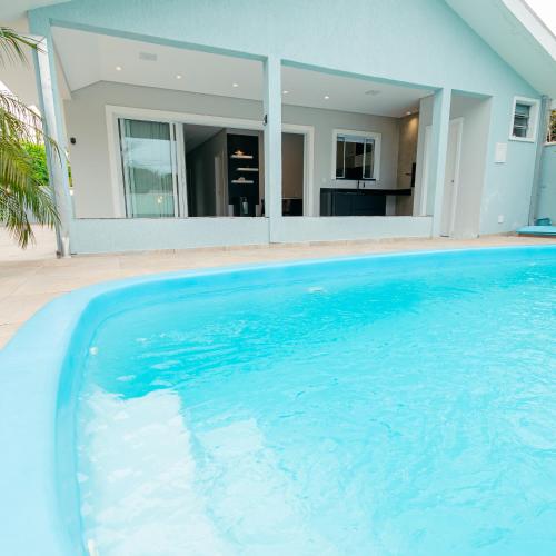 a large blue swimming pool in front of a house at M&M House - Casa com Piscina e Ar Condicionado em Matinhos in Matinhos