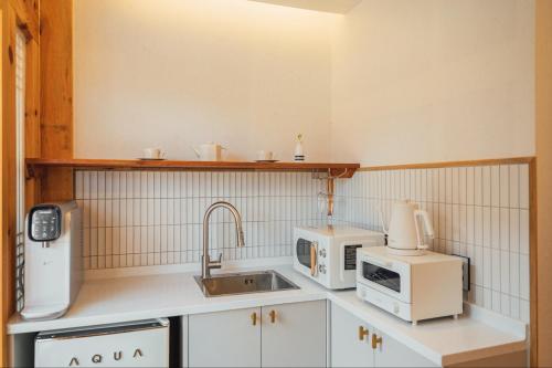 a kitchen with white appliances and a sink at Hanok Stay Seowa in Gyeongju
