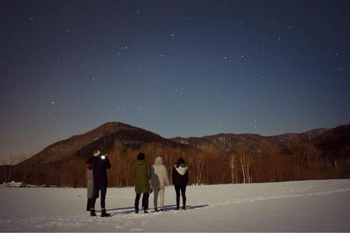a group of people standing in the snow at night at Farm Stay Ezura Farm in Engaru