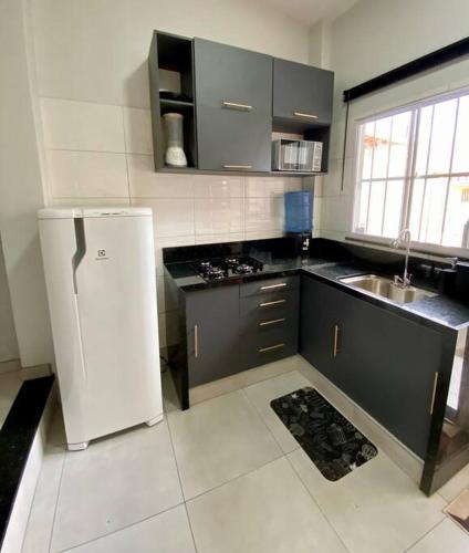 a kitchen with a white refrigerator and a sink at Loft Iron em capim macio in Natal