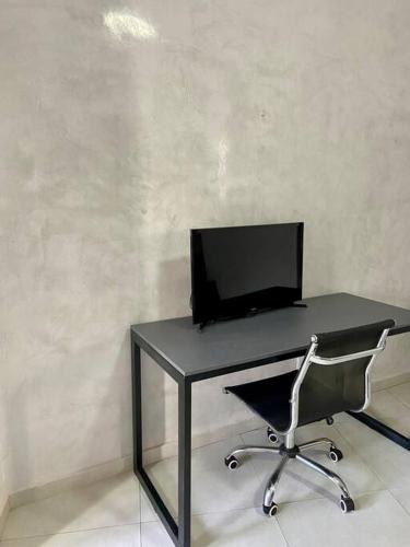 a desk with a computer monitor and a chair at Loft Iron em capim macio in Natal