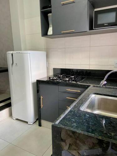 a kitchen with a white refrigerator and a sink at Loft Iron em capim macio in Natal