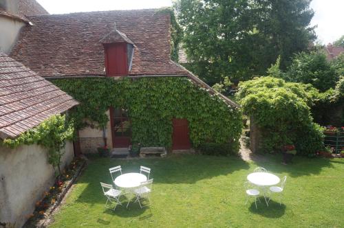 a house with two tables and chairs in the yard at La Grange in Nohant-Vic