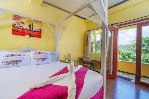 a bedroom with a bed and a desk and a window at Tropical Paradise View in Anse La Raye