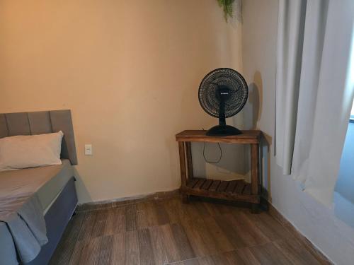 a room with a fan on a table next to a bed at Pousada Piu-piuu Cajazeiras in Salvador