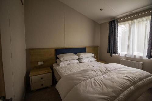 a bedroom with a bed with white sheets and pillows at Luxury Lodge With Decking In Hunstanton At Manor Park Ref 23144K in Hunstanton