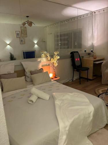 a bedroom with a large white bed and a desk at Appartement Relaxe in Carquefou