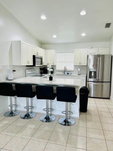 a kitchen with white cabinets and a counter with bar stools at Spacious Home at Lehigh Acres in Lehigh Acres