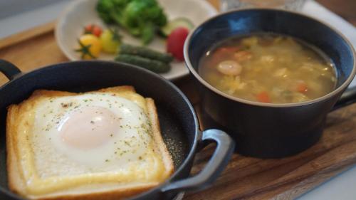 a table with a bowl of soup and a piece of bread with a egg in at Farm Stay Ezura Farm in Engaru