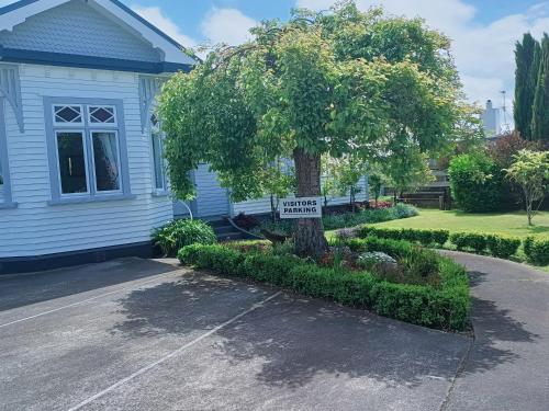 a sign on a tree in front of a house at Fossil Coast B&B in Hawera