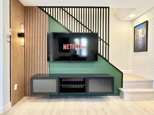 a living room with a tv and a staircase at Les Suites des Chutes - La Royale in Boischâtel