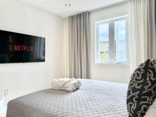 a white bedroom with a bed and a window at Les Suites des Chutes - La Royale in Boischâtel