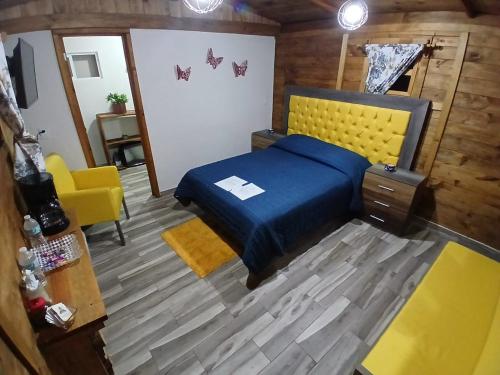 a bedroom with a blue bed and a yellow chair at El descanso casa-hotel zacatlán. in Zacatlán