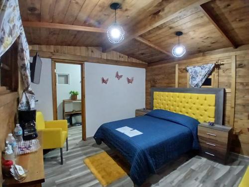 a bedroom with a blue bed and a yellow chair at El descanso casa-hotel zacatlán. in Zacatlán
