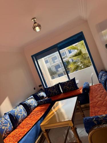 Una sala de estar con un sofá azul y una ventana. en Bel Appartement vue piscine, en Minaret de Mansuria