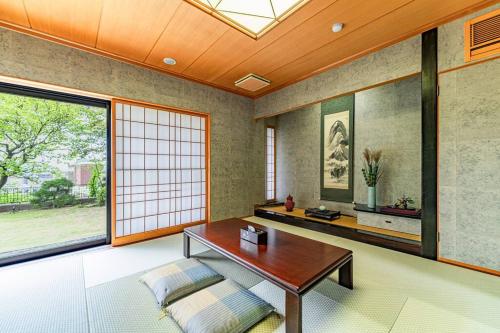 a living room with a table and a window at DOGO TEI -Sasaki- in Matsuyama