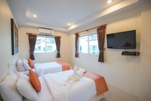 a hotel room with two beds and a flat screen tv at At Kamala Hotel in Kamala Beach