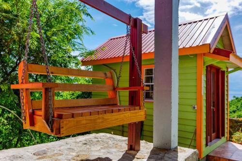 a swing in front of a green house at Tropical Paradise View in Anse La Raye