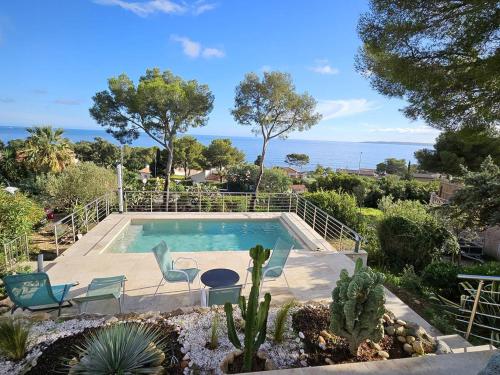 - une piscine dans un jardin avec des chaises et des cactus dans l'établissement Villa charmante avec piscine, clim, wifi et parking à 300m de la mer - FR-1-768-107, aux Issambres