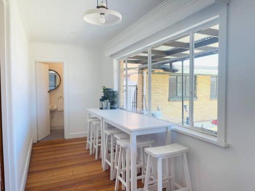 a dining room with a white table and white stools at D133 St Alban station stay in St Albans