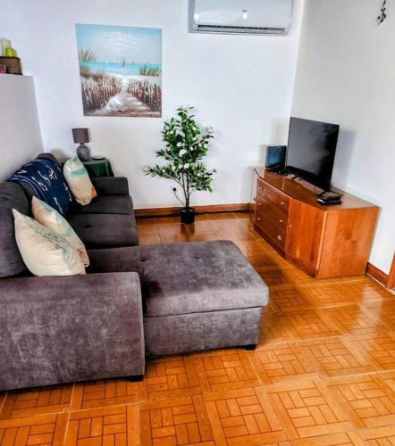 a living room with a couch and a tv at Ocean's Edge in Horta