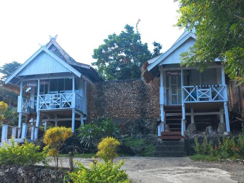 a blue house with a stone wall at Scuba Republic Beach Bungalows in Bira